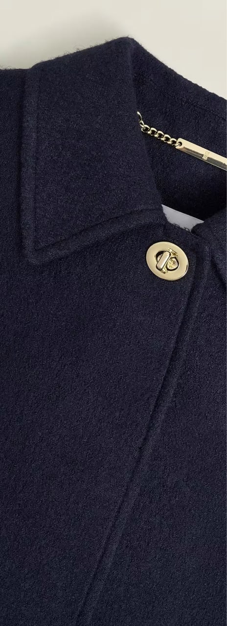 A gallery of four images including one image of a model wearing a navy coat, and three smaller images displaying details of the coat.
