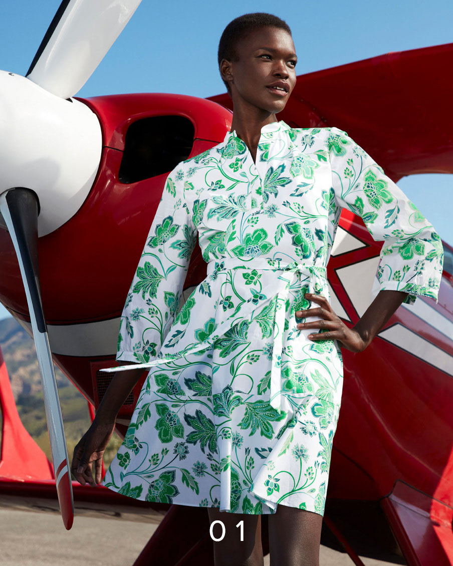 Image of model pictured in front of an aeroplane wearing a floral print summer dress.