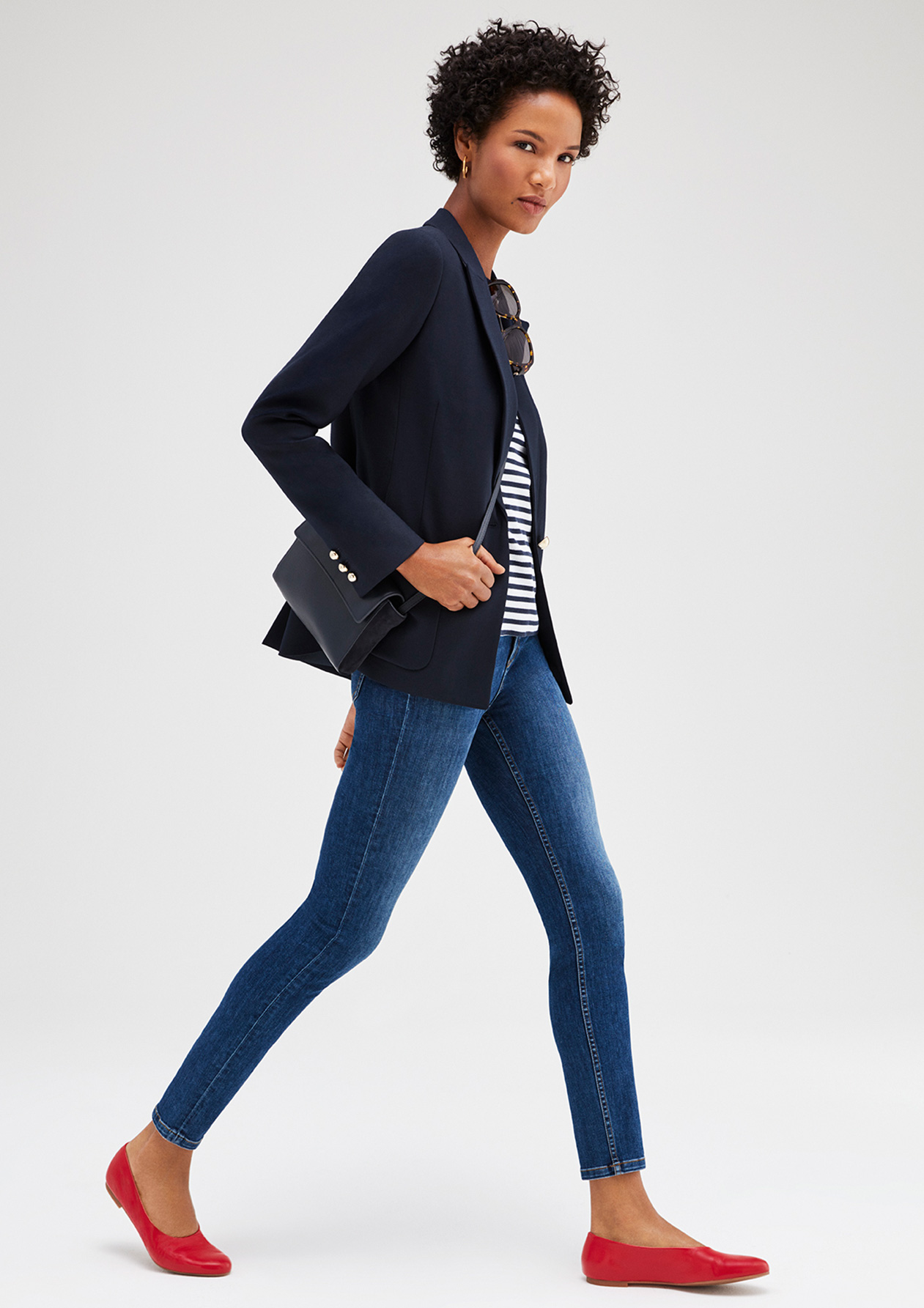 Nail relaxed style, model wears a casual outfit consisting of a classic navy blazer, striped top, blue jeans and red flats. 