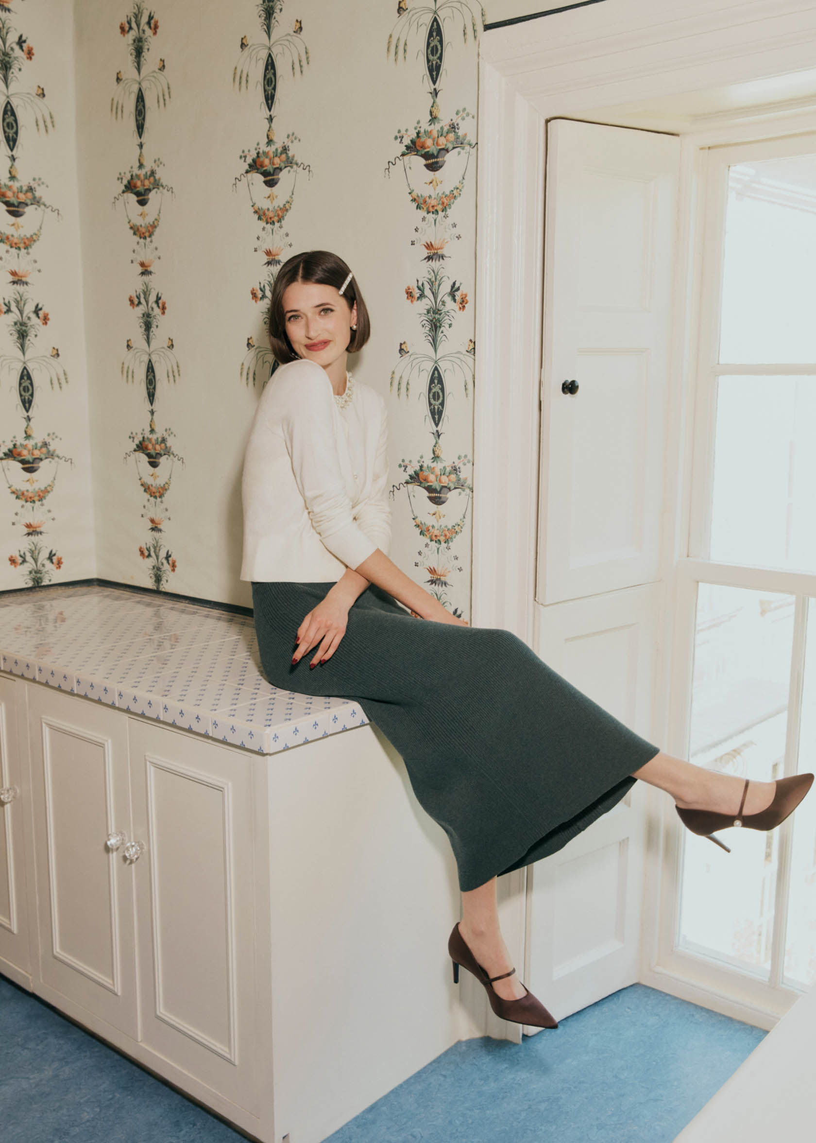 Image of a model sitting on a cupboard wearing a knitted two-piece.
