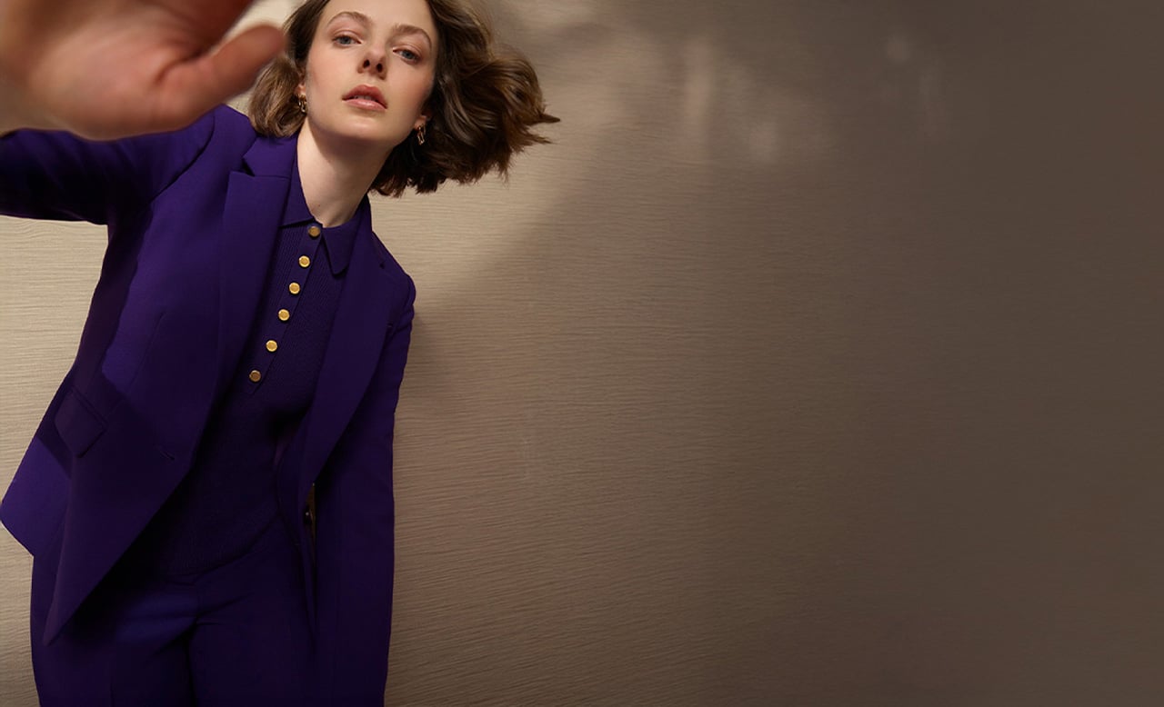 A woman wearing a purple tailored suit.