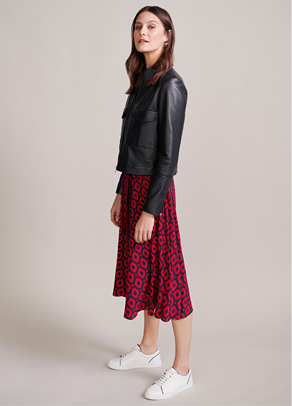 Collage of a green satin blouse, black knitted jacket, jeans, white trainers and a leopard print bag that together create an outfit.