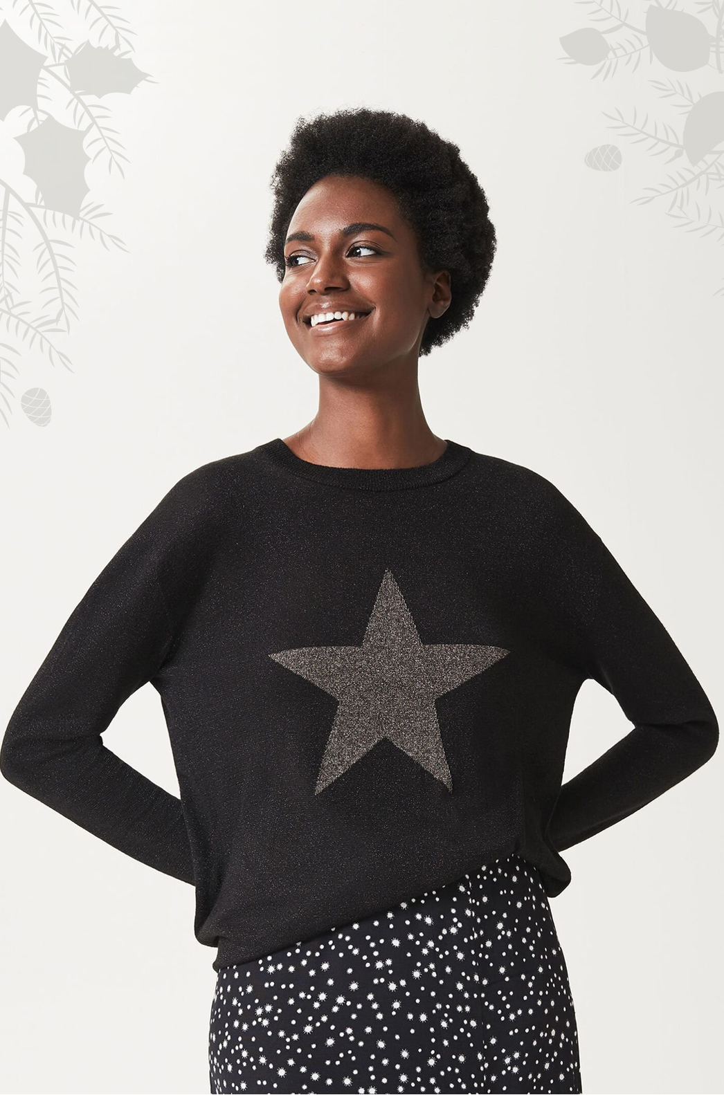 Model photographed wearing a black jumper with a gold star motif.