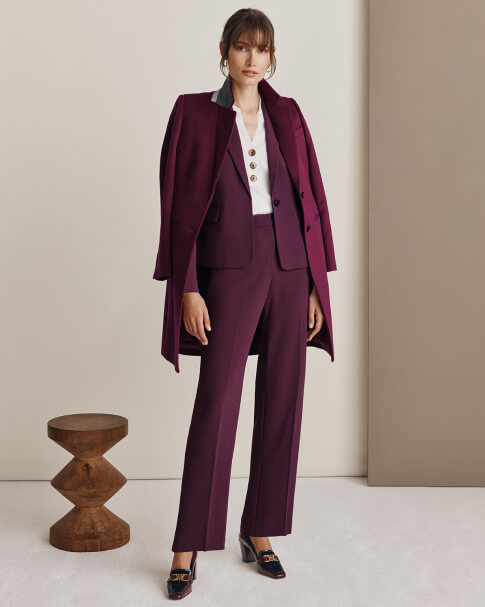 Hobbs model wears a plum-coloured trouser suit with a ribbed knit top and heeled loafers.