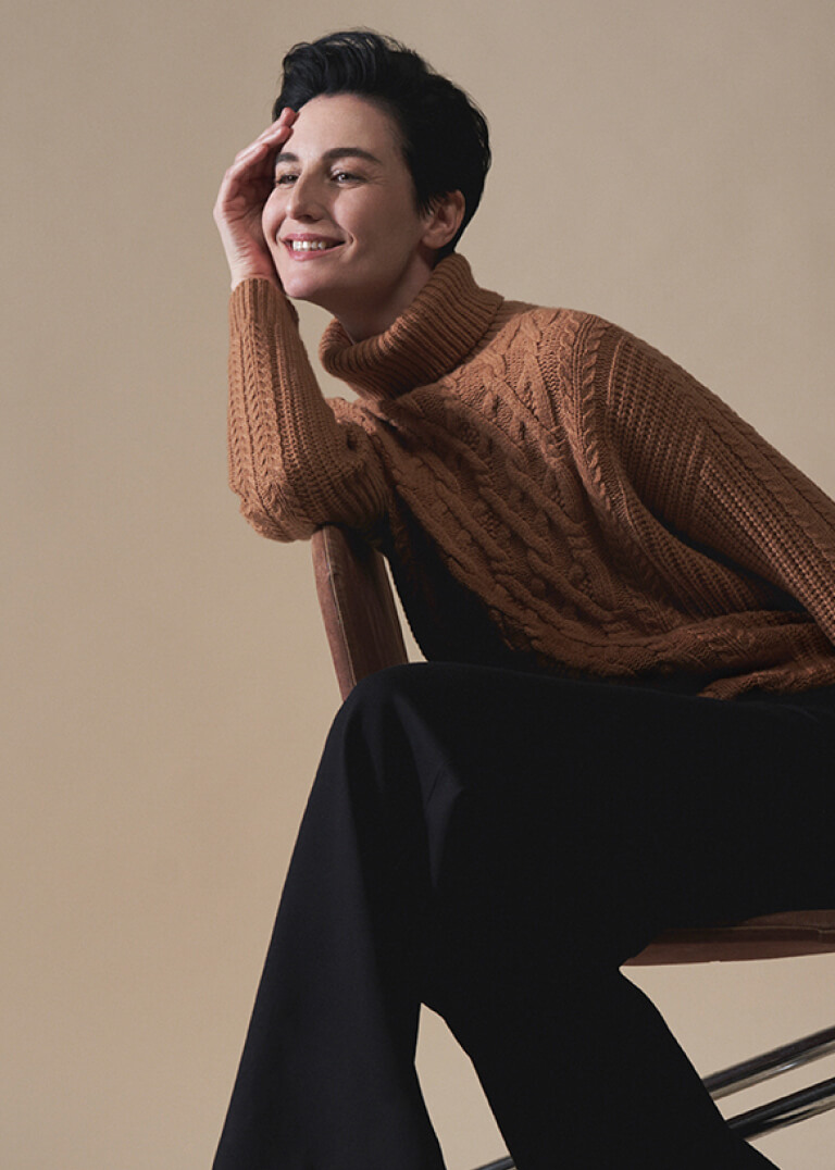 Model Erin O'Connor photographed sitting, wearing a Hobbs tan cable knit jumper.