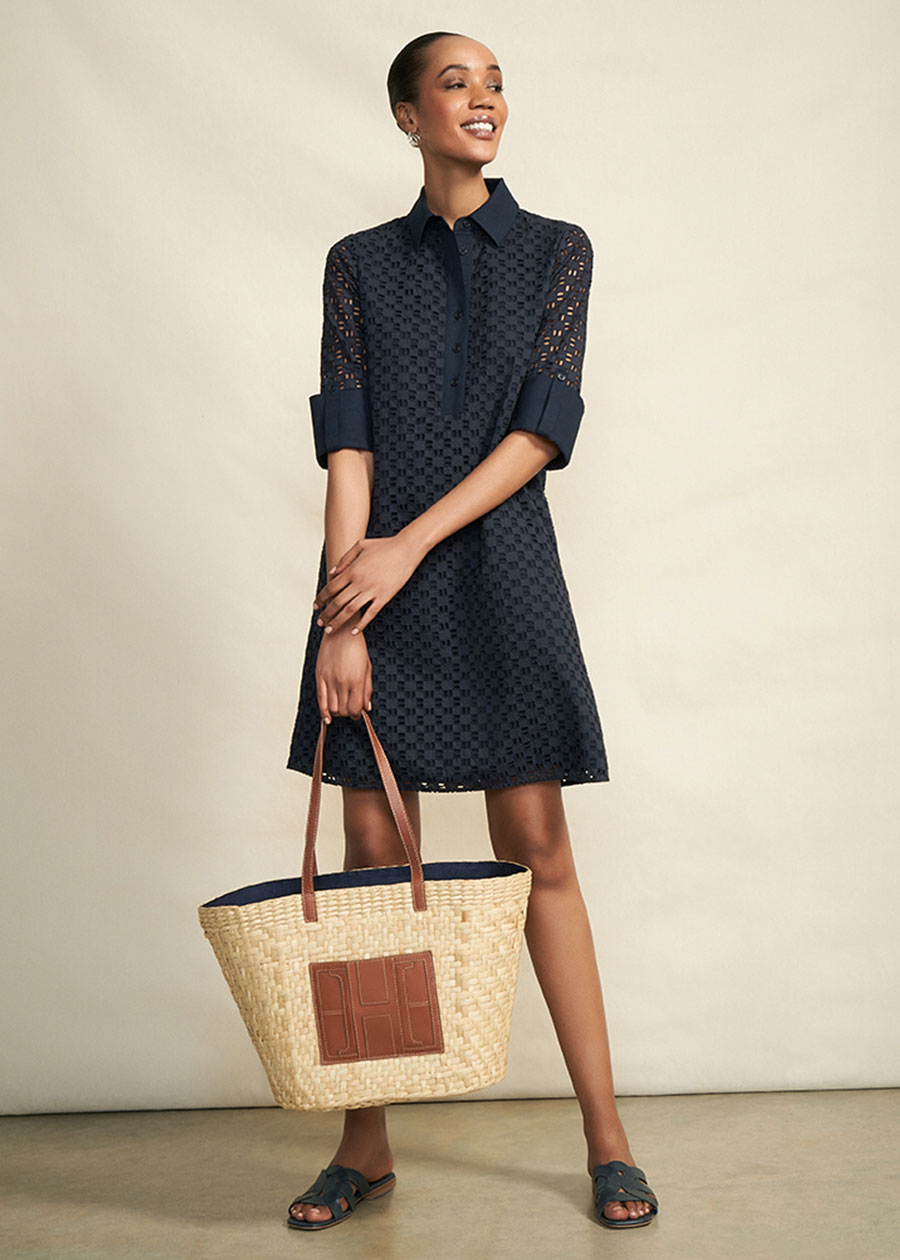 Model photographed against a canvas background wearing a Hobbs navy broderie anglaise dress.