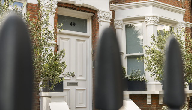 The front of an Edwardian red brick London home with a white front door