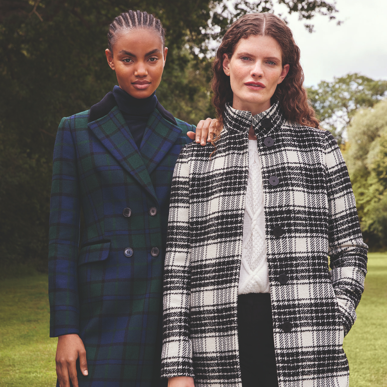 Image of two models wearing check wool coats standing in front of a sculpture.