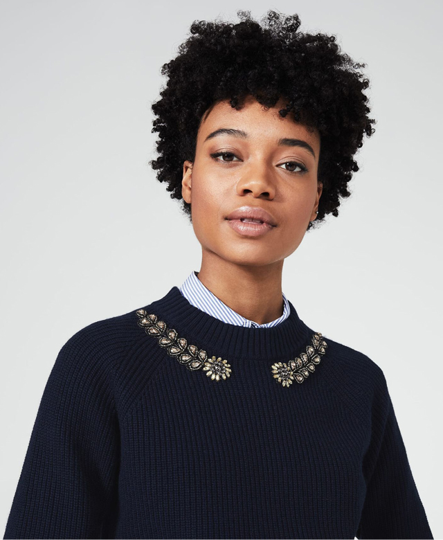 Model photographed wearing a navy jumper with embellished neckline.