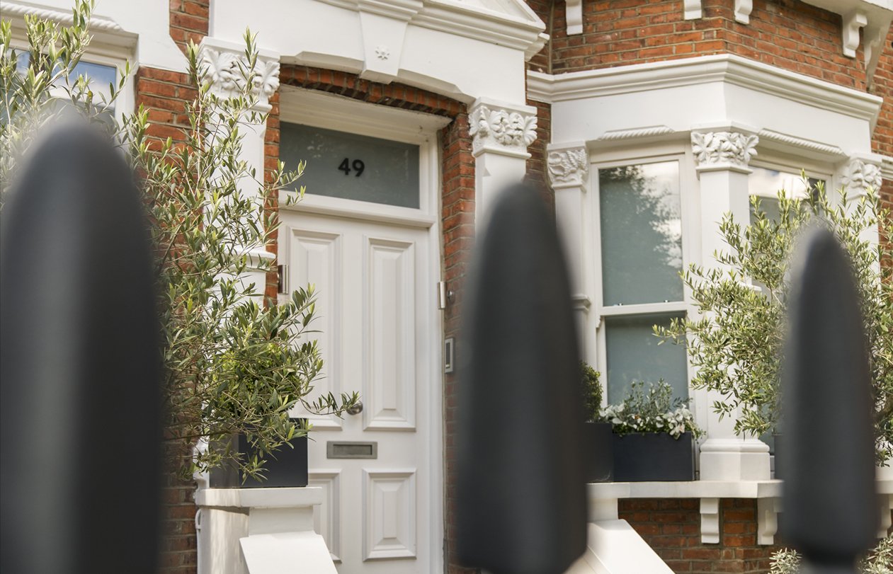 The front of an Edwardian red brick London home with a white front door