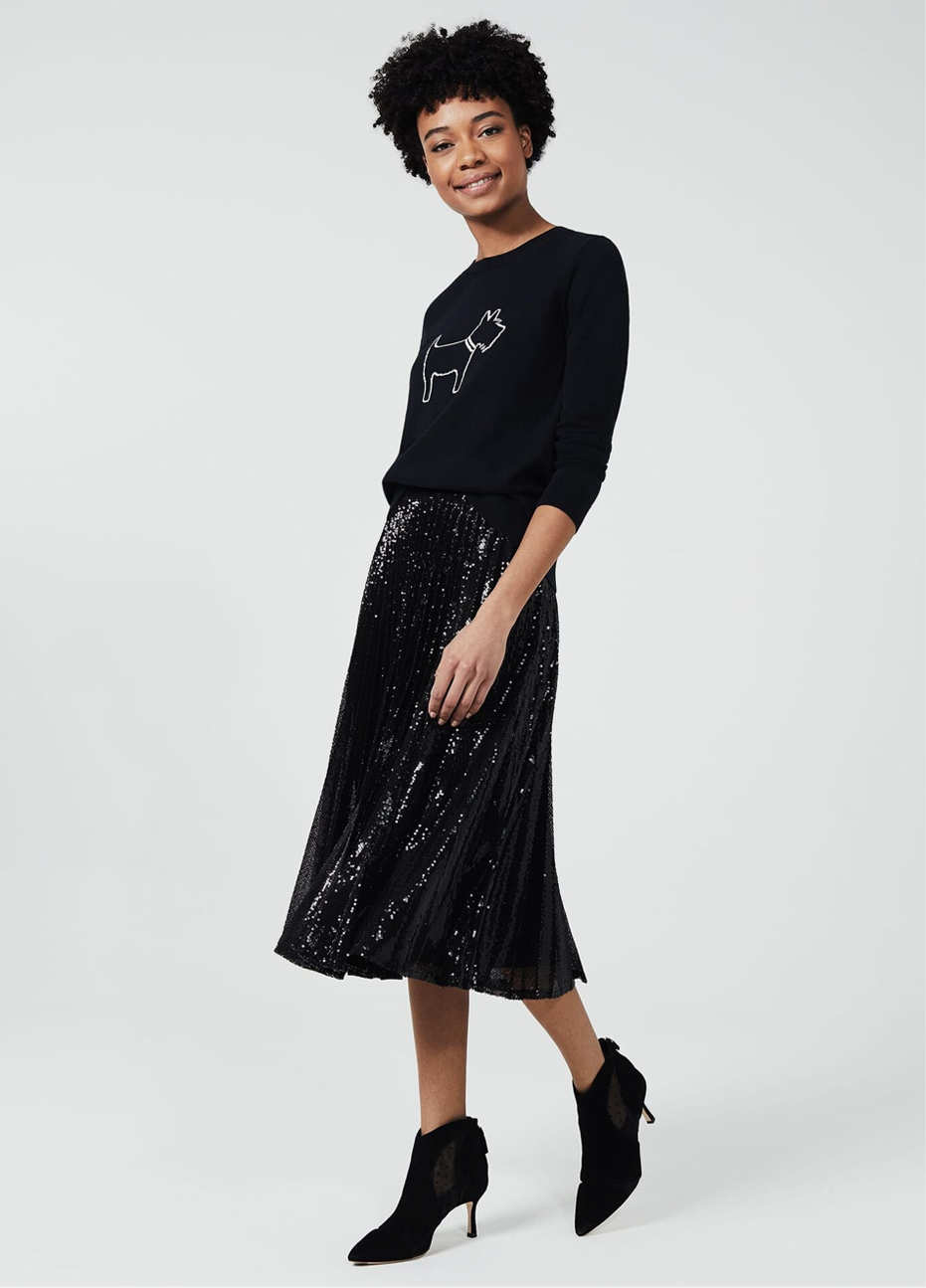 Hobbs model wearing a fun knitted jumper featuring illustration of a dog, styled with a sequin skirt with black pointed suede boots.