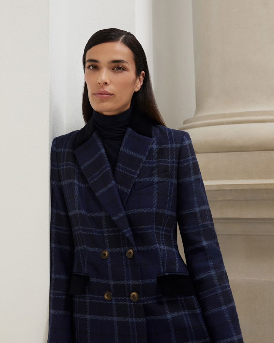 Model photographed leaning on a wall wearing a Hobbs navy checked coat.
