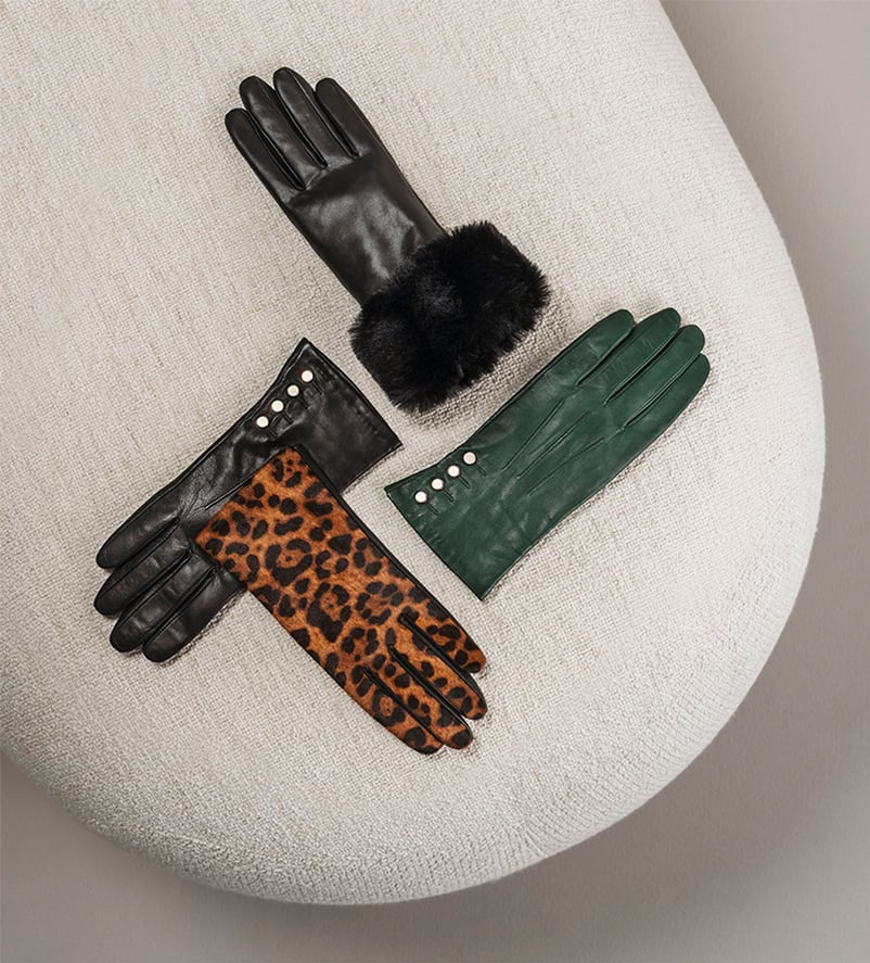 Selection of black, green and leopard print leather gloves on a footstool.