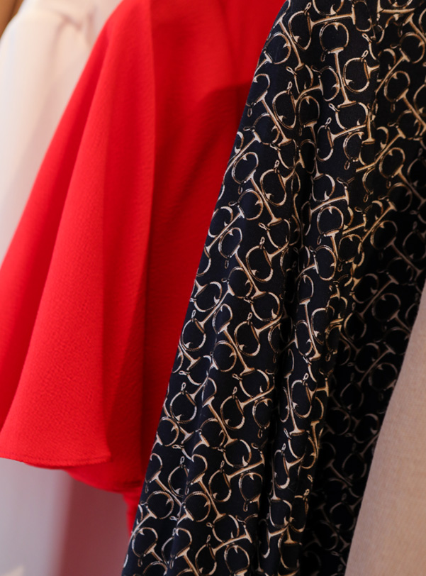 Interior shot of wardrobe with red, cream and patterned black clothing