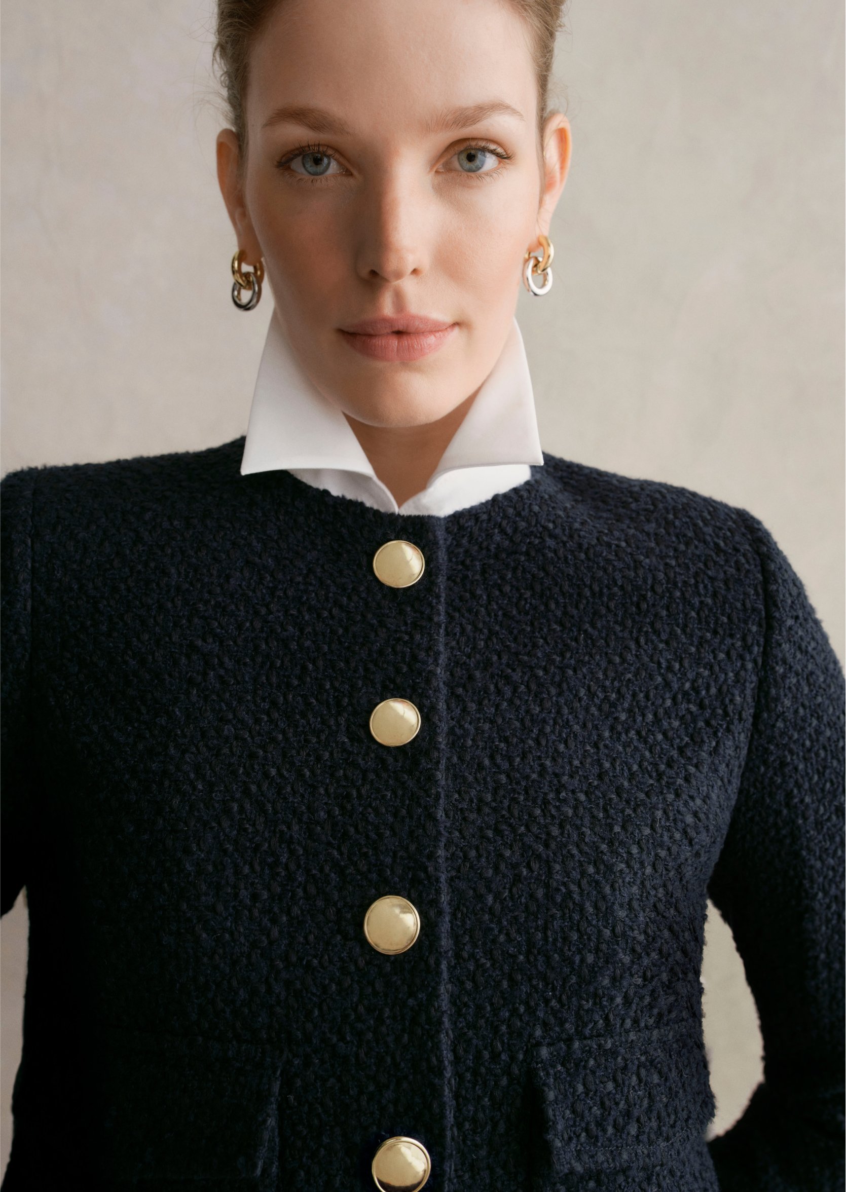A gallery of three images displaying a model wearing a cropped navy jacket