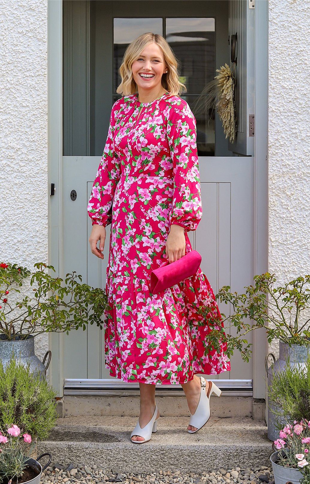 Lifestyle blogger @all.thats.pretty photographed in her garden wearing Hobbs' Marilyn pink floral midi dress with Kali ivory heels.