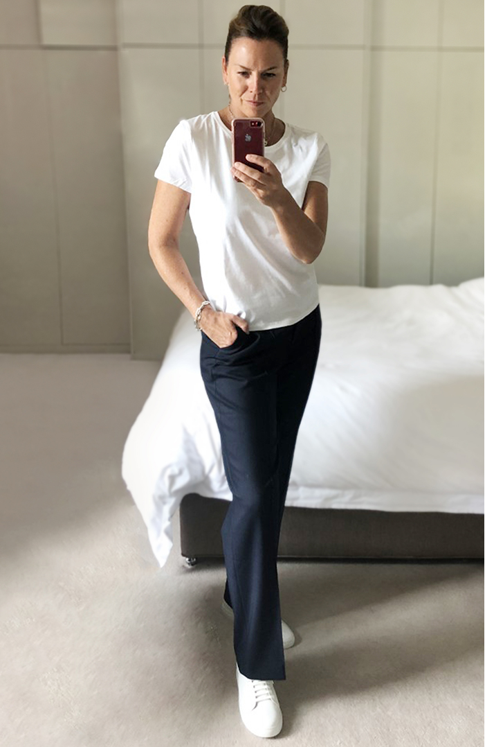 An outfit for relaxing - Sally wears a simple but stylish white t shirt and straight-leg trousers with white leather trainers. 