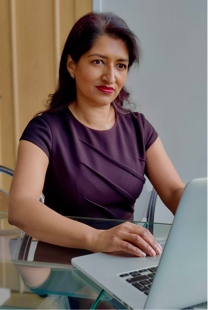 Photographed working from home, fashion blogger Monika Mandal wears Hobbs petite black Ophelia dress.