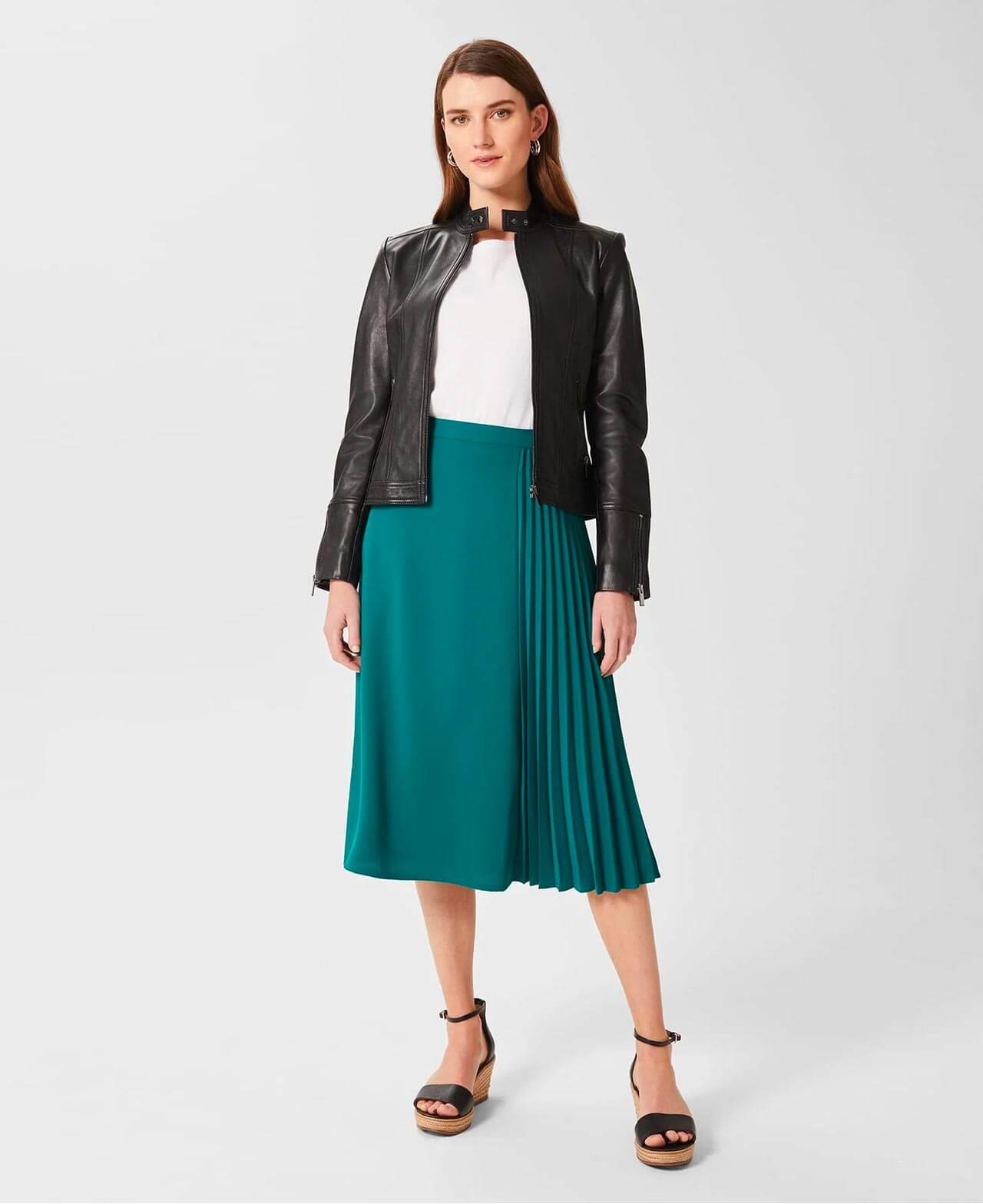 Hobbs model wears a leather jacket, pleated midi skirt and espadrille wedge sandals.