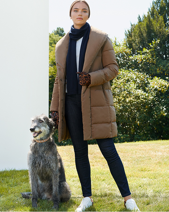 Model wears a long beige puffer jacket, dark blue jeans and white leather trainers