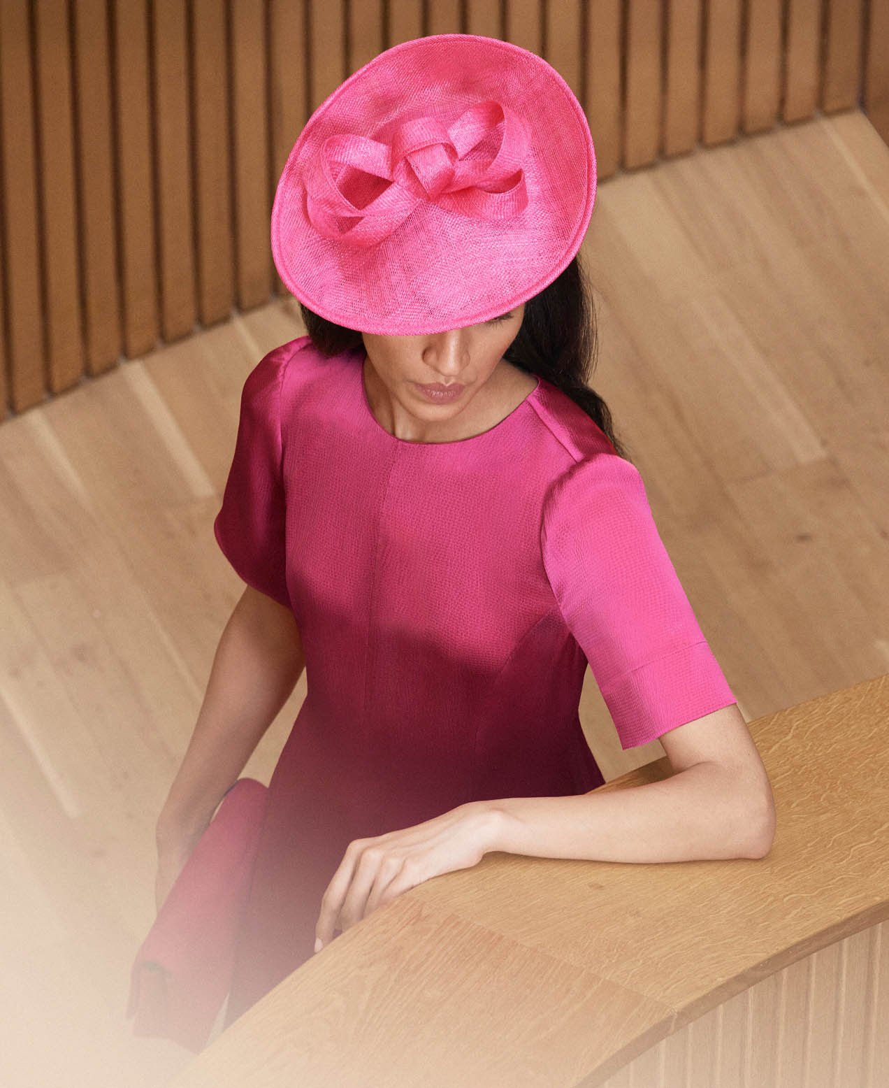 A woman wearing a bold pink fascinator.