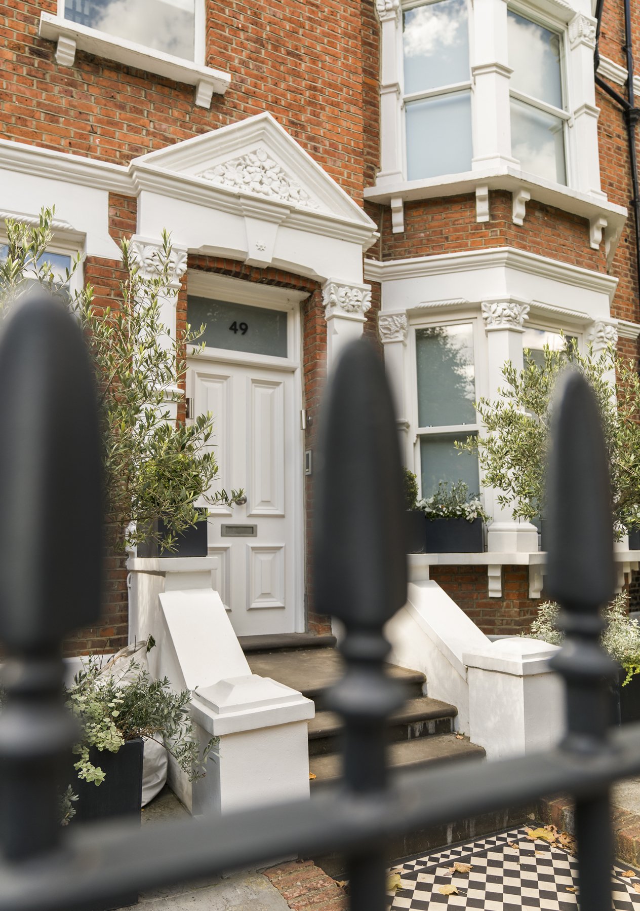 A red brick Edwardian house with a white front foor with a black and white tiled stairs