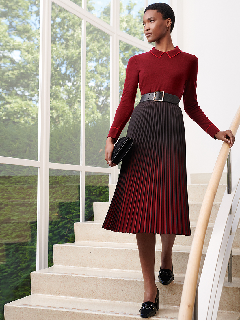 Model wears a red midi dress with a black leather belt and a black cluth bag