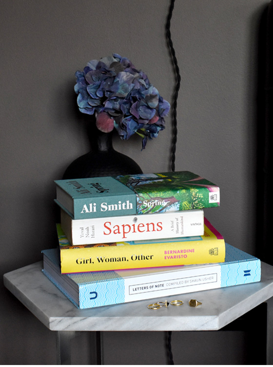 A pile of books situation on Jen's bed side. 