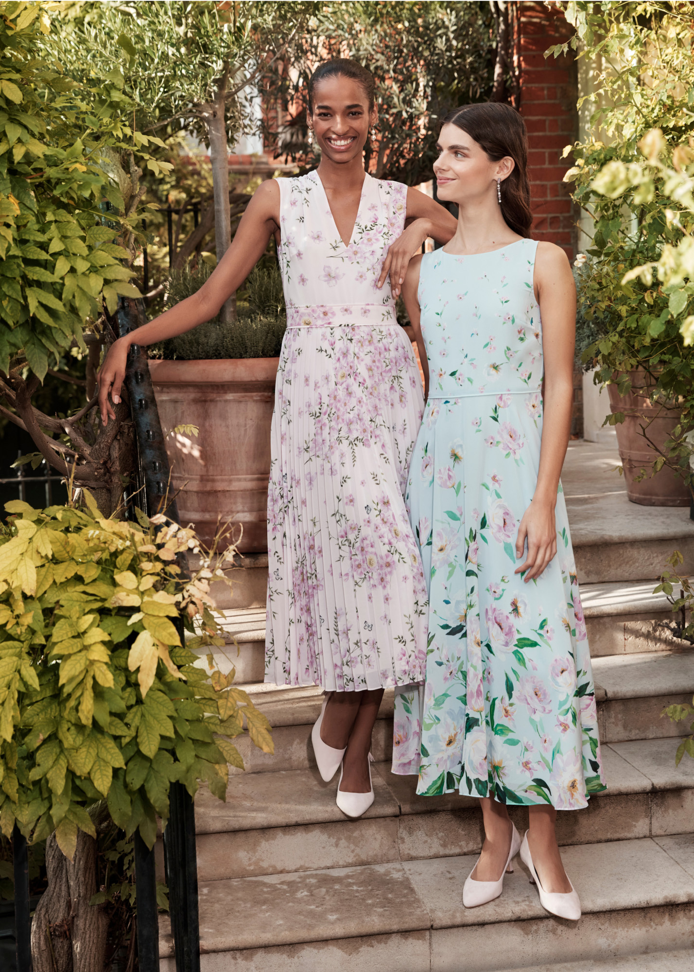 Image of two models standing outside a wedding venue wearing bridesmaid dresses.