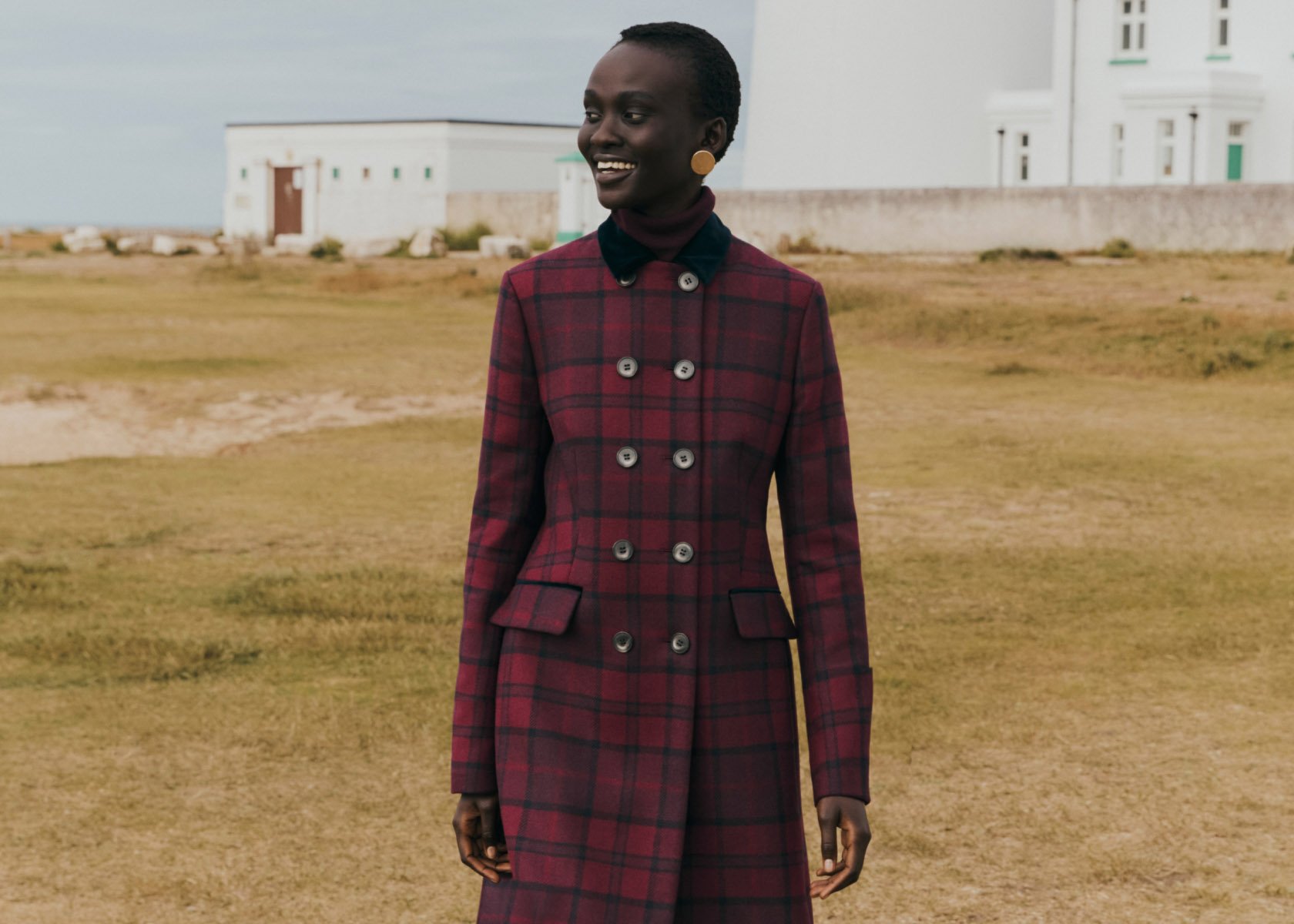 Image of a model on the coast wearing a long, wool, check coat.