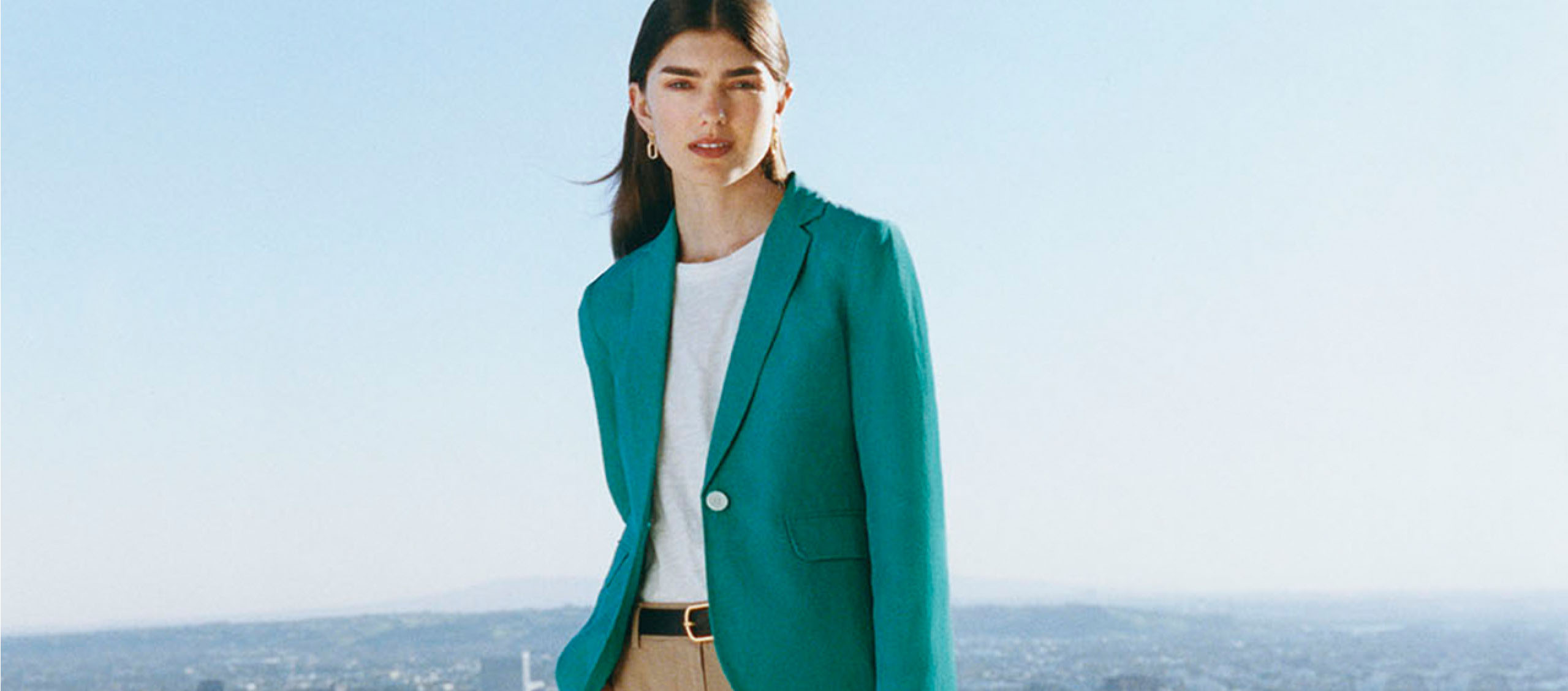 Image of model pictured in front of a skyline wearing a linen blazer over a t-shirt with chino trousers.