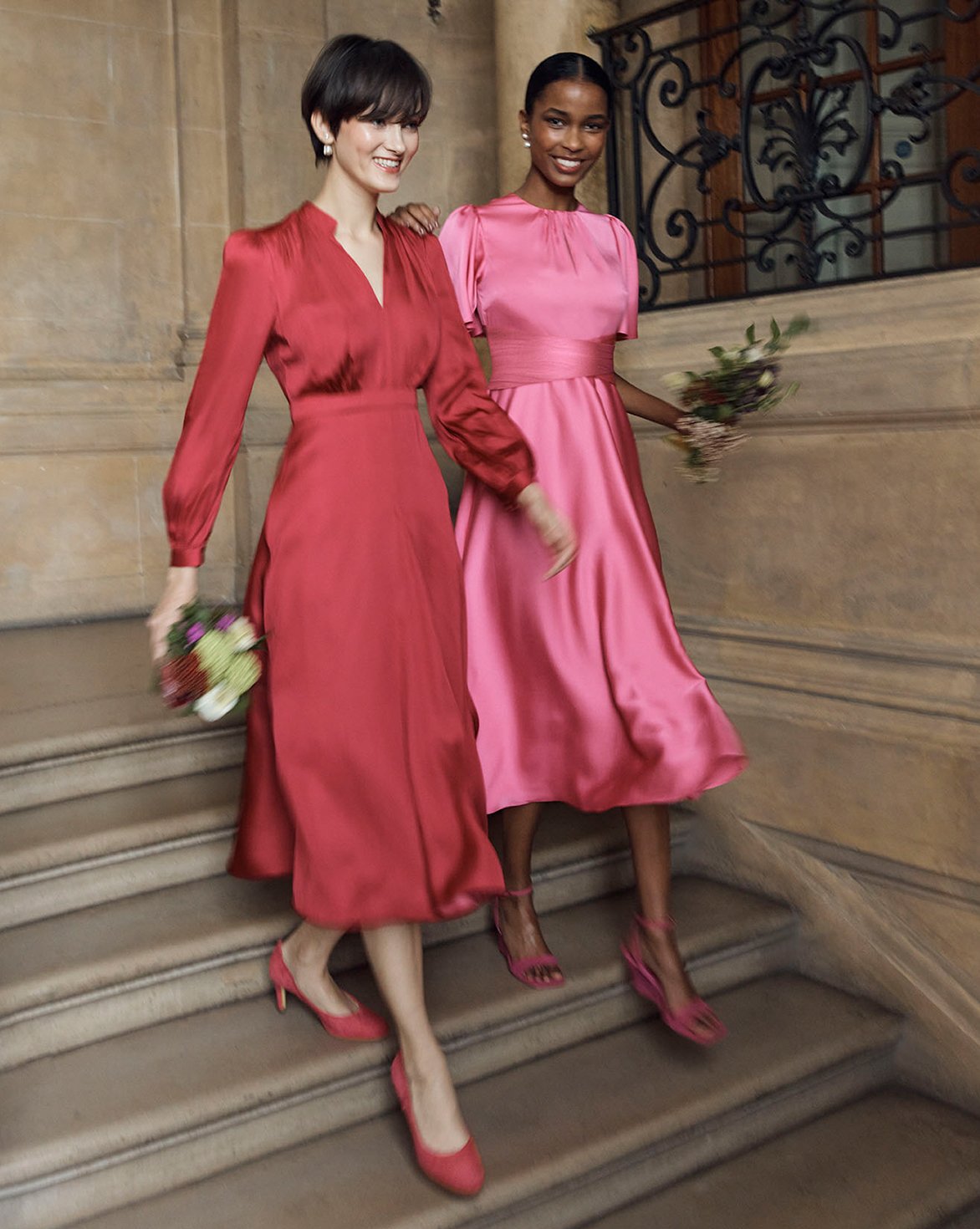 Hobbs models walk down stairs in elegant occasion dresses.