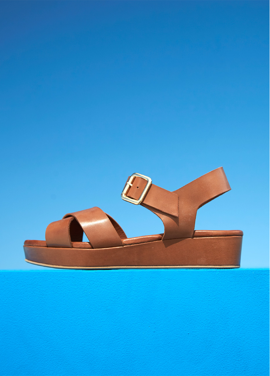 rown leather flatform sandal from Hobbs set against a blue background.