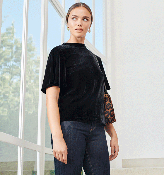 Model photographed in a home wearing a black velvet top with jeans.