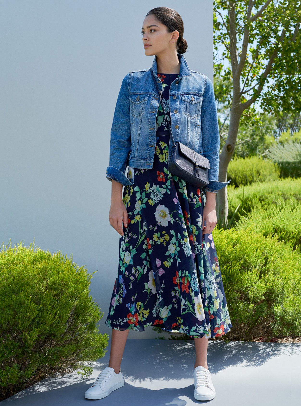 Blue denim jacket worn with a midi floral dress, white trainers and blue leather crossbody bag by Hobbs.