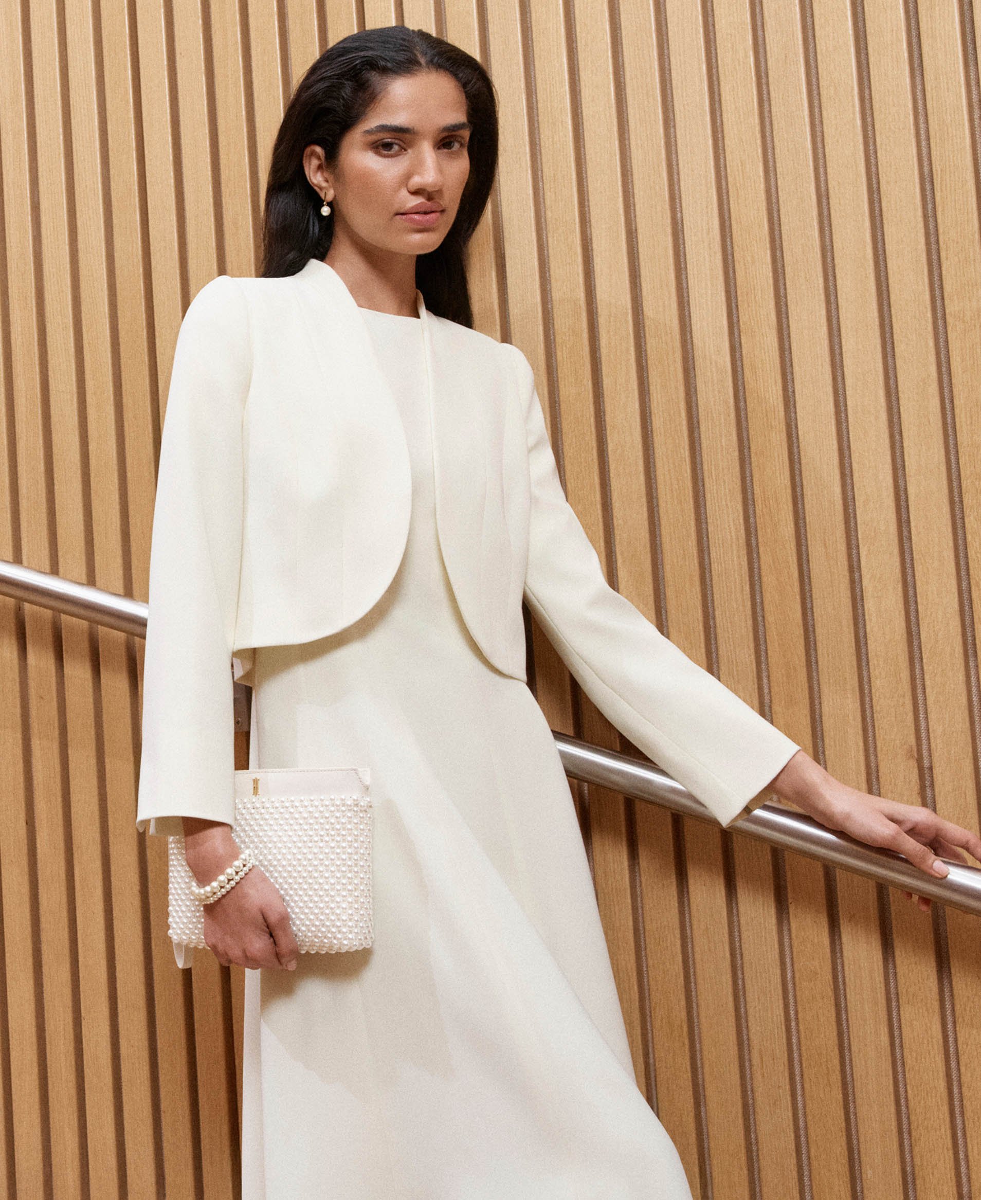 A woman wearing a butter yellow occasion dress and coordinating jacket