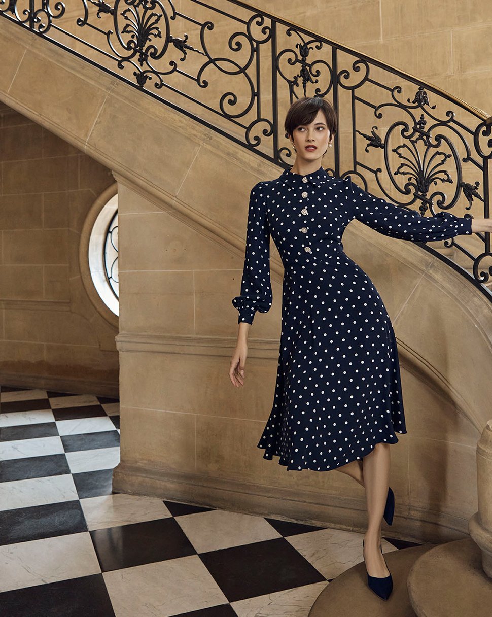 Hobbs model wears a navy polka dot dress with diamante buttons.