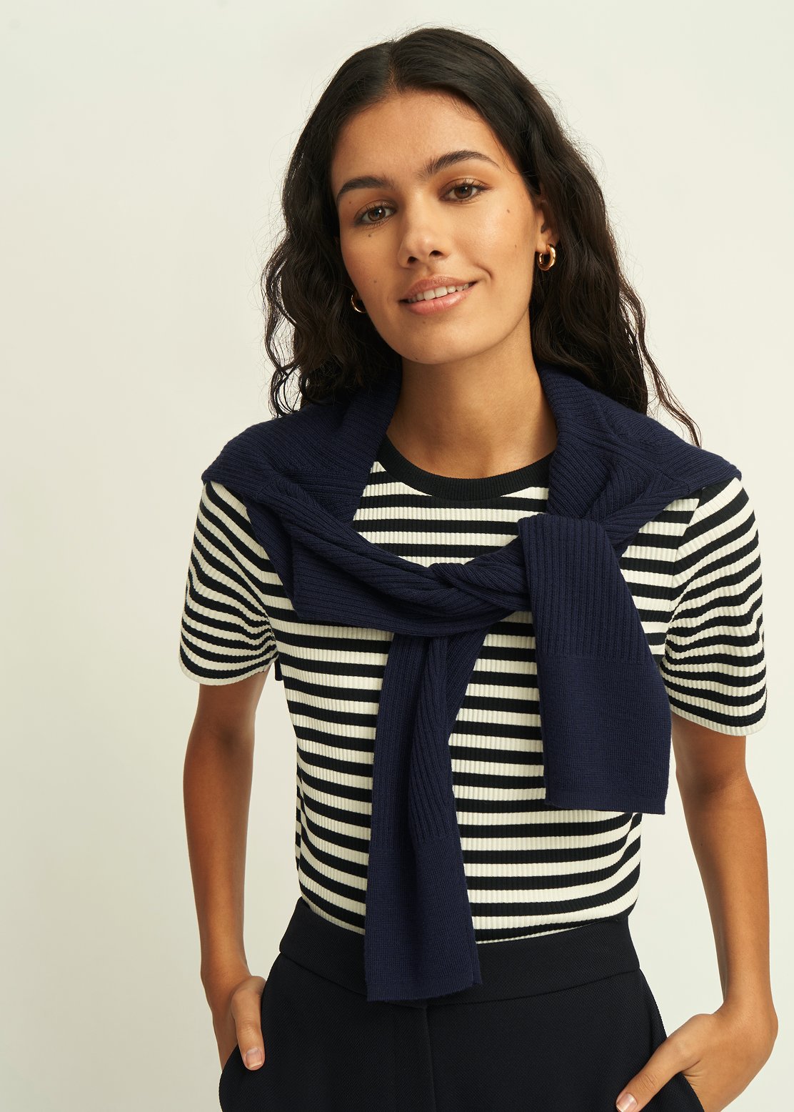 A girl wearing a striped t-shirt and cardigan over her shoulders