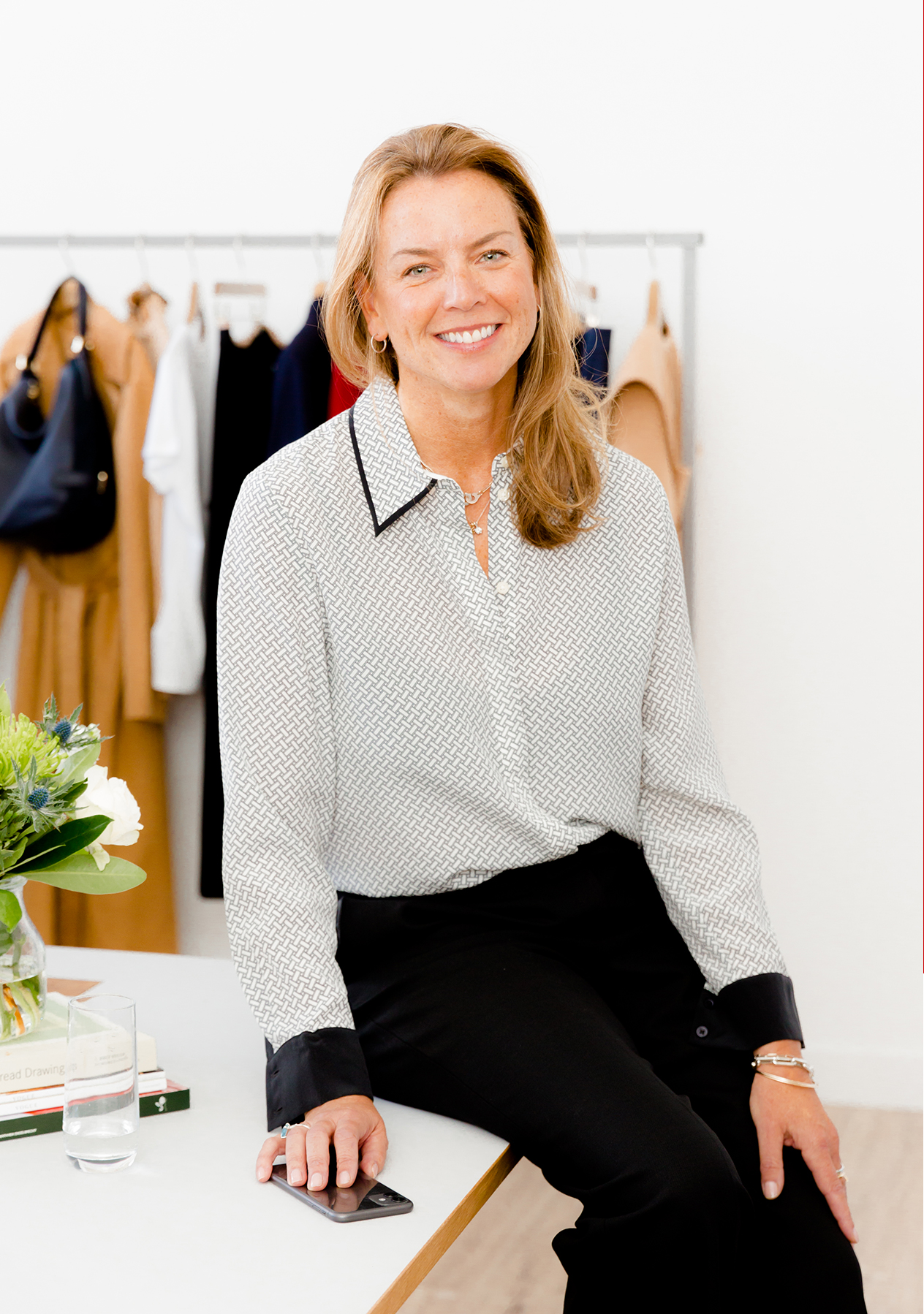  Hobbs' Product Director, Sally Ambrose, photographed wearing a silk shirt while leaning on an office desk.