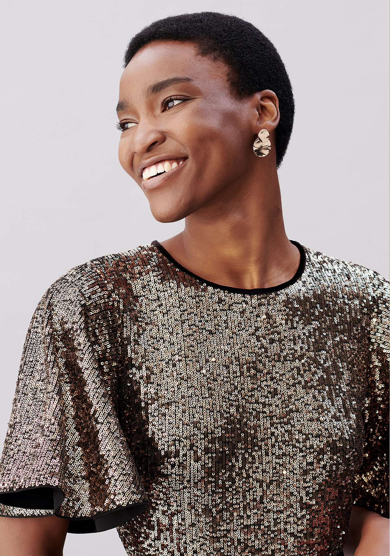 Model wears a sequin-embellished dress and earrings from Hobbs.