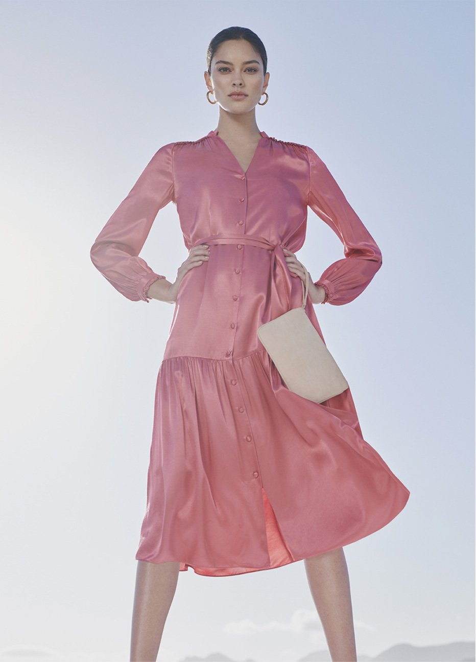 Pink satin dress with waist-tie detail for weddings and occasions, paired with matching court shoes and a wristlet clutch both in pale pink and hoop earrings, by Hobbs. 