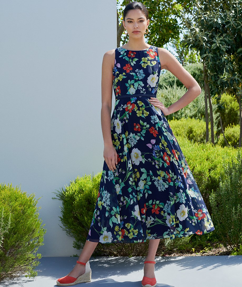 Navy midi length dress with floral print worn with espadrilles by Hobbs.