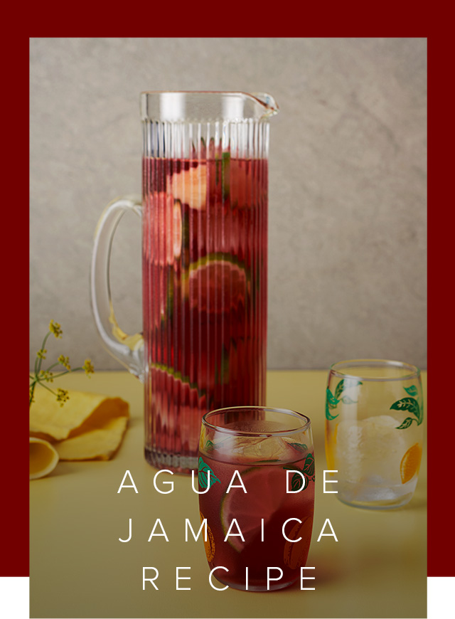 Image of jug and glasses filled with Agua De Jamaica and sliced fruit.