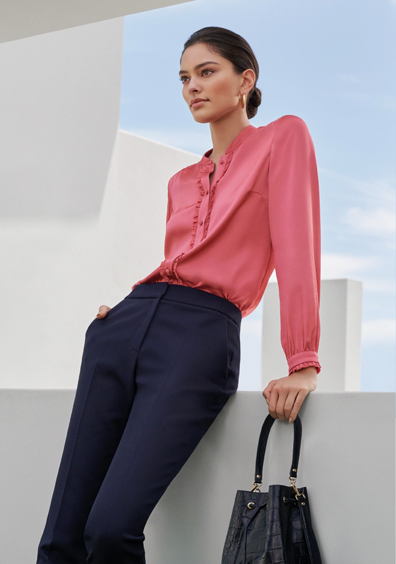 Satin shirt in pink worn with navy blue tailored trousers and a black leather bucket bag, by Hobbs.