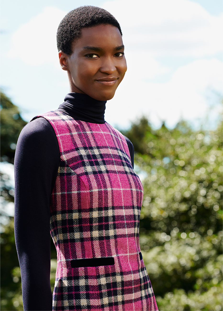 Close-up image of model wearing a checked tunic dress over a roll neck top. 