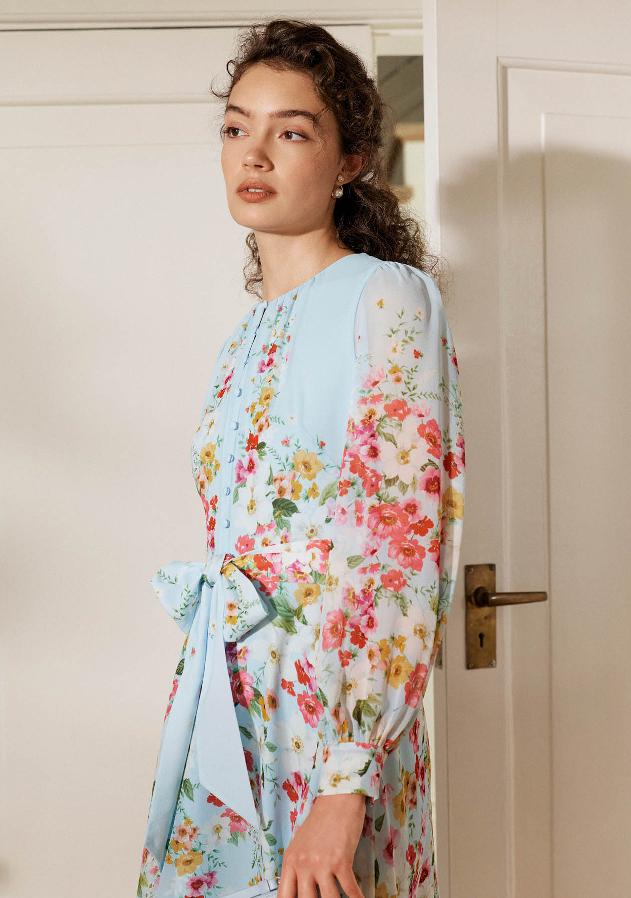 A woman wearing a floral print silk dress.