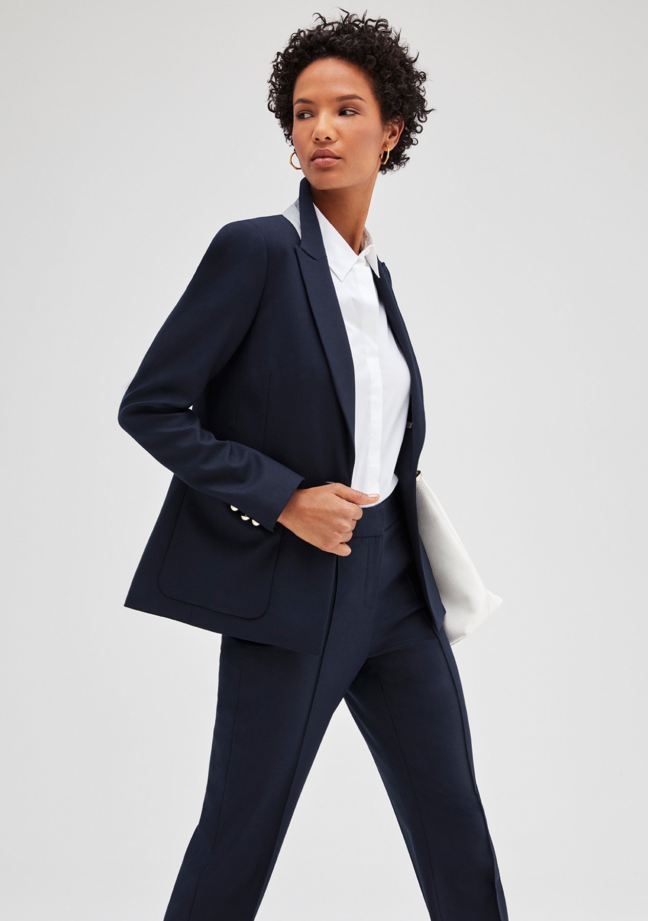 Model poses in a classic nevy blue tailored trouser suit styled with a white shirt