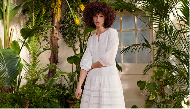 Model wearing a Hobbs cream summer dress in a conservatory.  