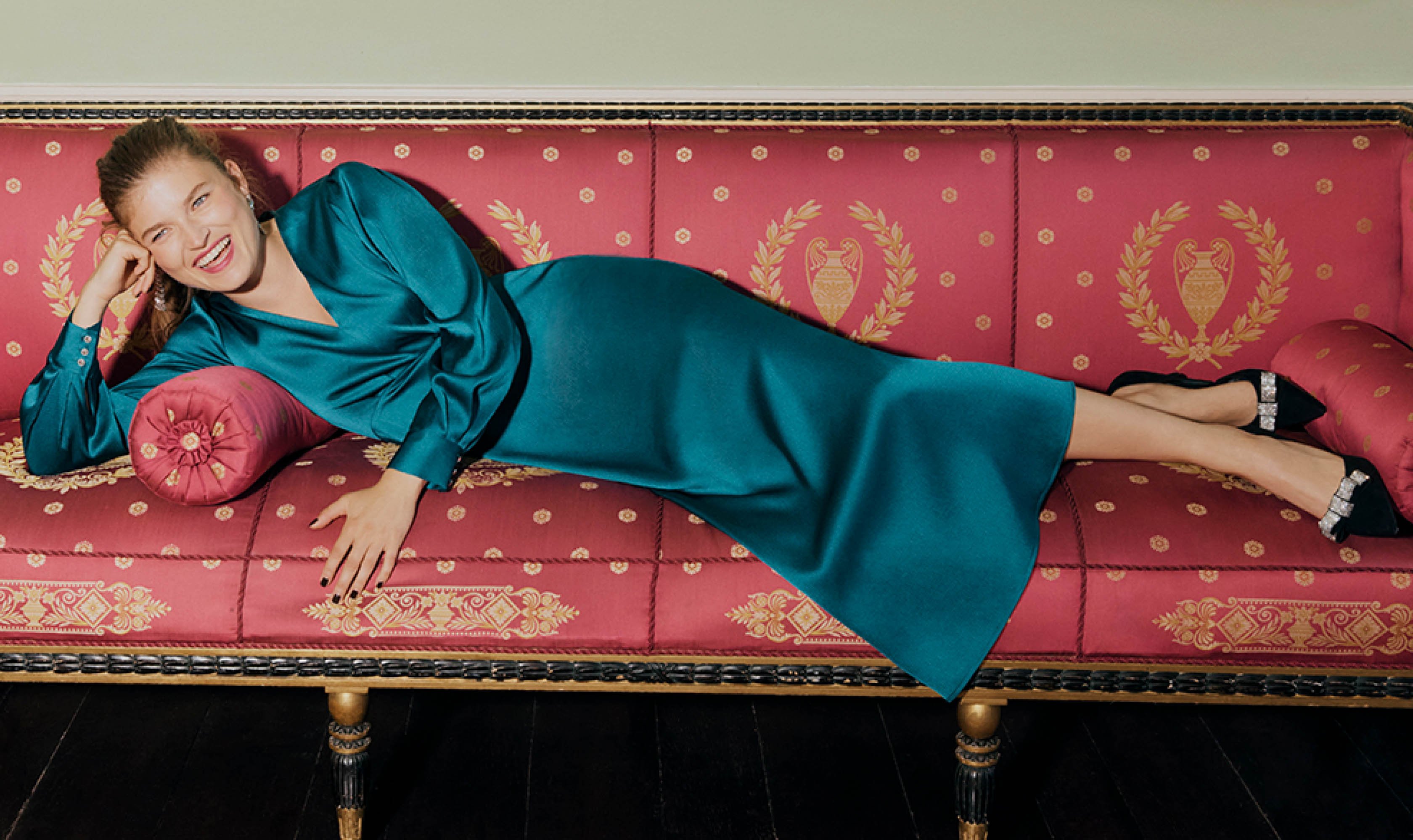 Image of a model lying down in a teal satin dress.