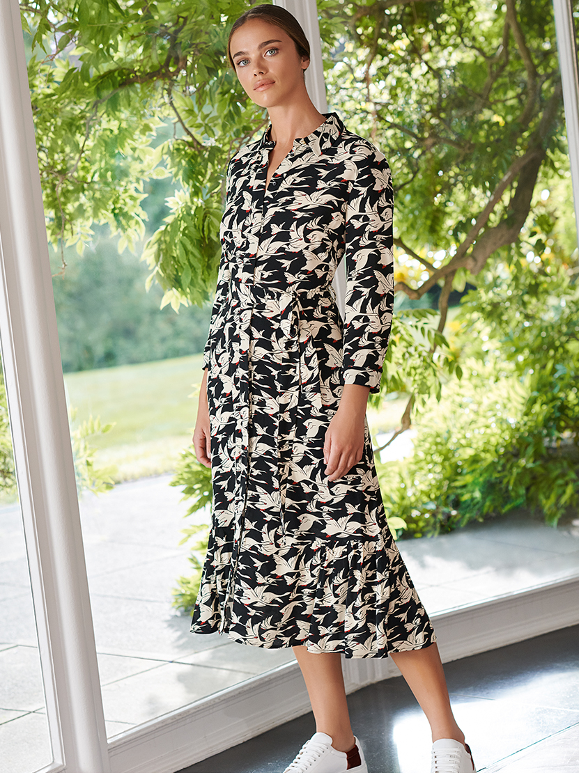 Model wears a beige and black belted midi dress